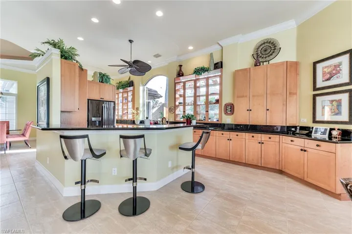 Kitchen featuring a breakfast bar, black fridge, a healthy amount of sunlight, and ceiling fan