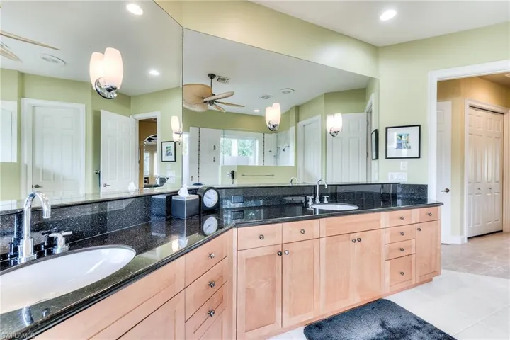 Bathroom featuring tile patterned flooring, ceiling fan, walk in shower, and vanity