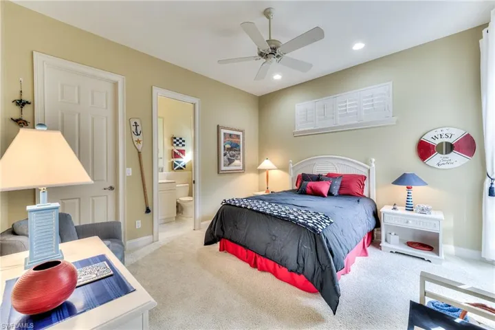Carpeted bedroom featuring ensuite bathroom and ceiling fan