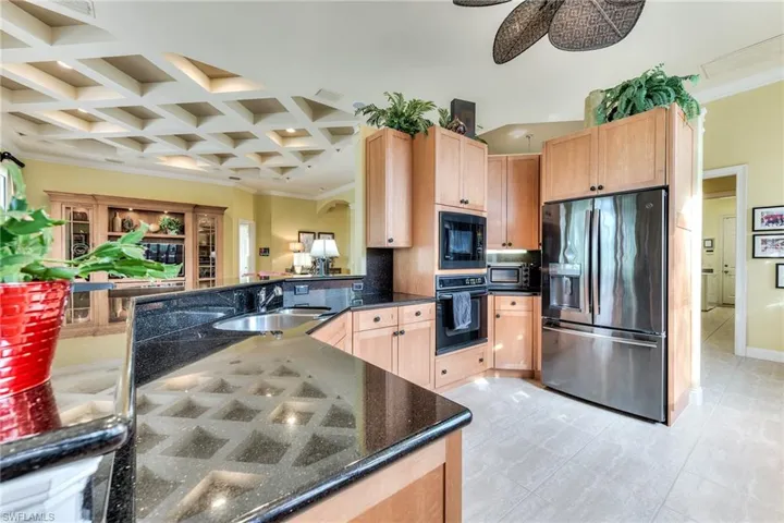 Kitchen with sink, black appliances, beam ceiling, coffered ceiling, and light brown cabinets