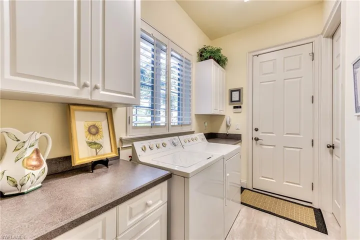 Washroom featuring washer and dryer, cabinets, and light tile patterned flooring