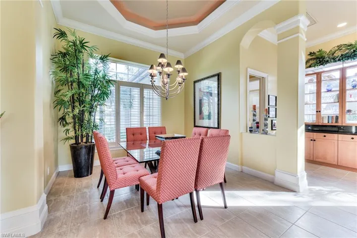 Dining room featuring a raised ceiling, a chandelier, plenty of natural light, and ornamental molding