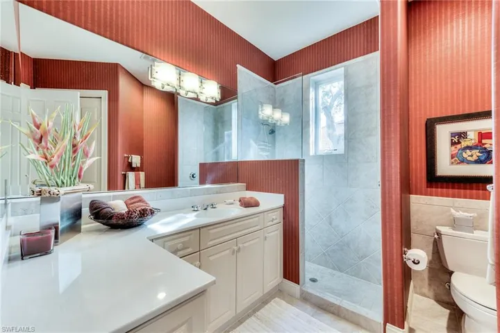 Bathroom with tile walls, a tile shower, toilet, tile patterned floors, and vanity