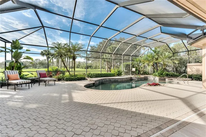 View of pool with a patio area and glass enclosure