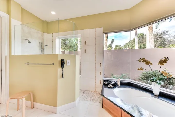 Bathroom with shower with separate bathtub and tile patterned floors