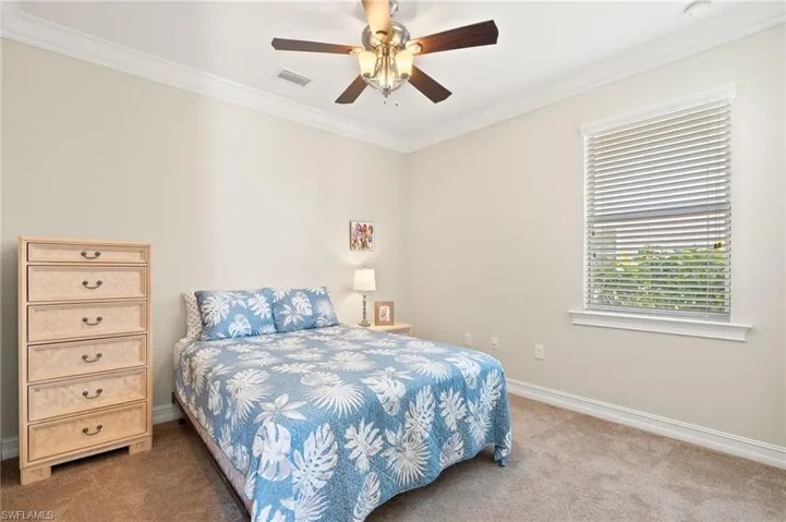 Carpeted bedroom with ceiling fan and ornamental molding