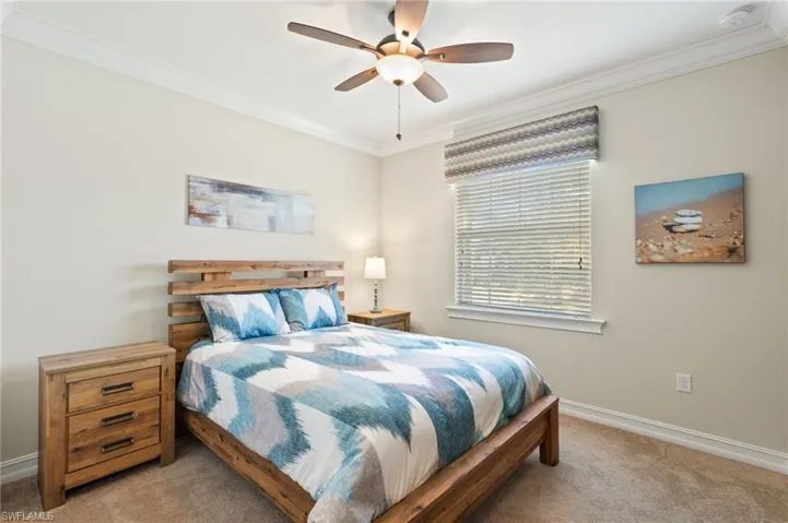 Carpeted bedroom featuring crown molding and ceiling fan