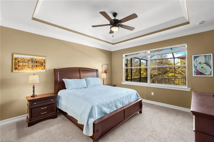 Carpeted bedroom with crown molding, a tray ceiling, and ceiling fan