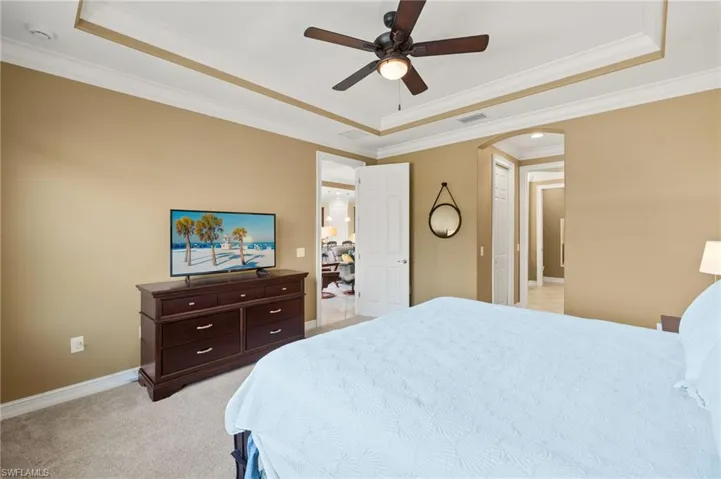 Bedroom with a raised ceiling, ornamental molding, and ceiling fan