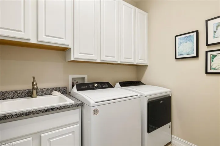 Washroom featuring washer and dryer, sink, and cabinets