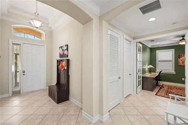 Foyer entrance featuring light tile patterned floors, crown molding, and ceiling fan
