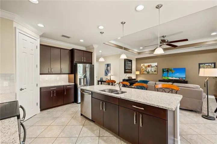 Kitchen with appliances with stainless steel finishes, decorative light fixtures, tasteful backsplash, sink, and a kitchen island with sink