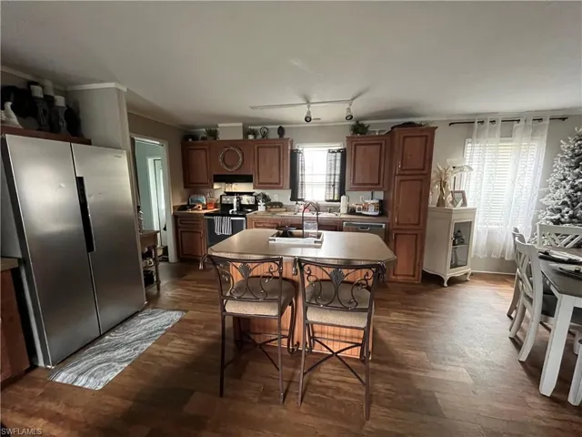 Kitchen featuring sink, rail lighting, dark hardwood / wood-style floors, a kitchen island, and stainless steel appliances