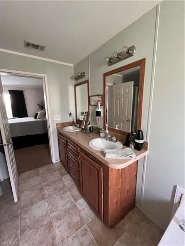 Master Bathroom with crown molding, double sink vanity, and tile patterned floors