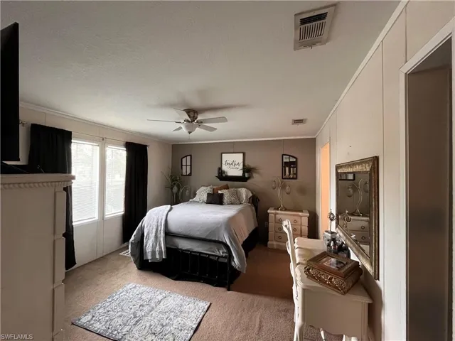 Carpeted bedroom featuring ceiling fan, crown molding, and a textured ceiling