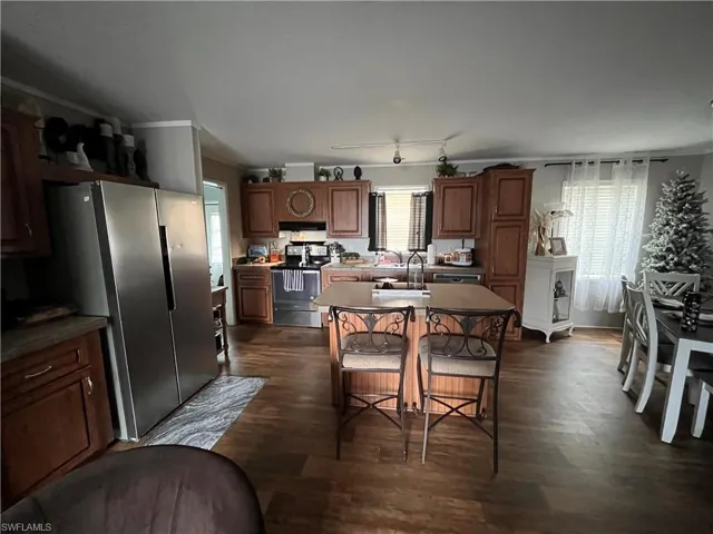 Kitchen featuring dark hardwood / wood-style floors, a center island, electric range, and stainless steel fridge