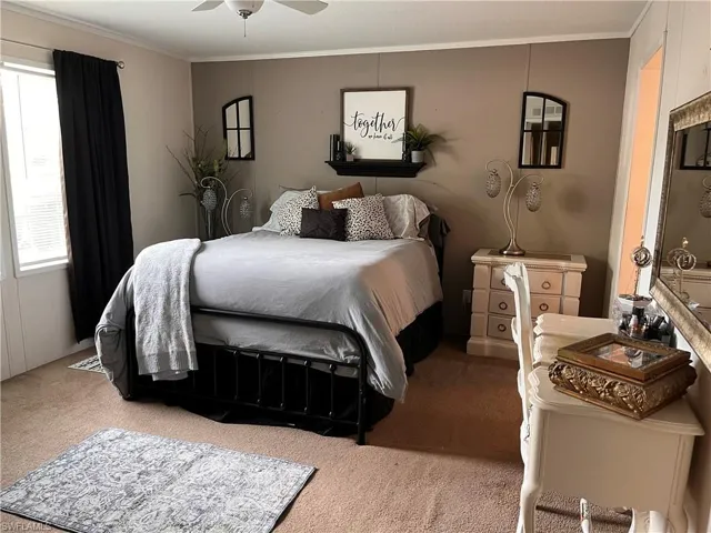 Carpeted bedroom featuring ceiling fan and ornamental molding