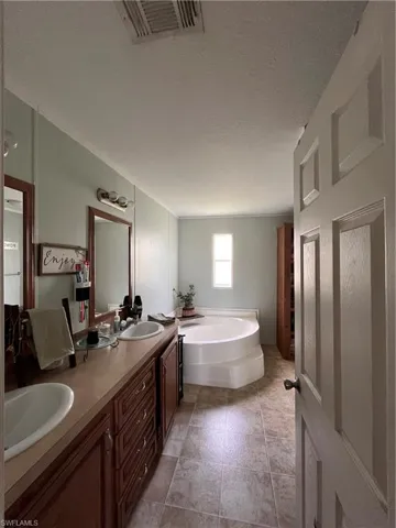 Master Bathroom featuring double sink vanity, a textured ceiling, tile patterned flooring, and a tub to relax in