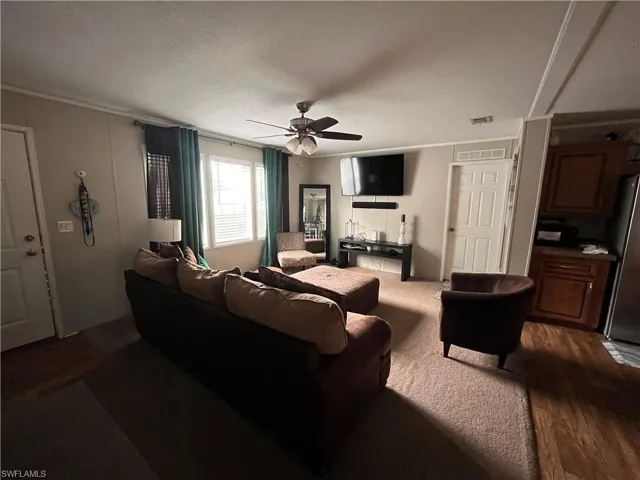 Living room with a textured ceiling, ceiling fan, and hardwood / wood-style flooring