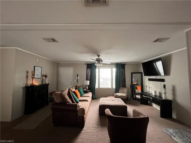 Living room with carpet floors, ornamental molding, and ceiling fan