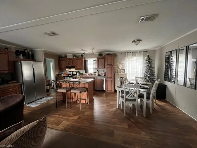 Dining area with dark hardwood / wood-style flooring, track lighting, and ornamental molding