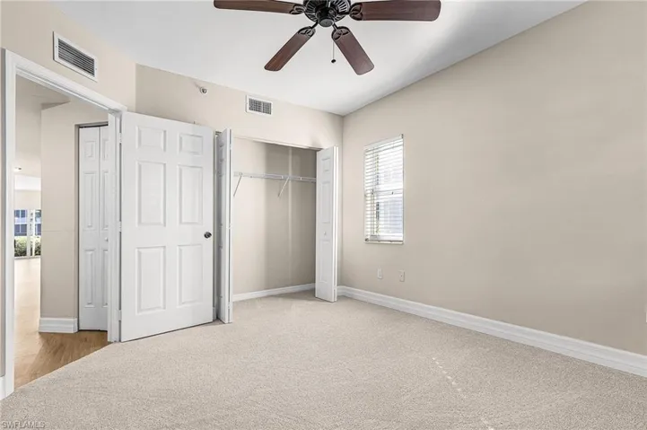 front Unfurnished bedroom with a closet, light carpet, and a ceiling fan- front of home