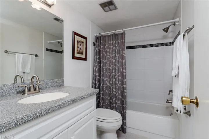 Full bathroom with tile patterned floors, visible vents, toilet, vanity, and shower / tub combo