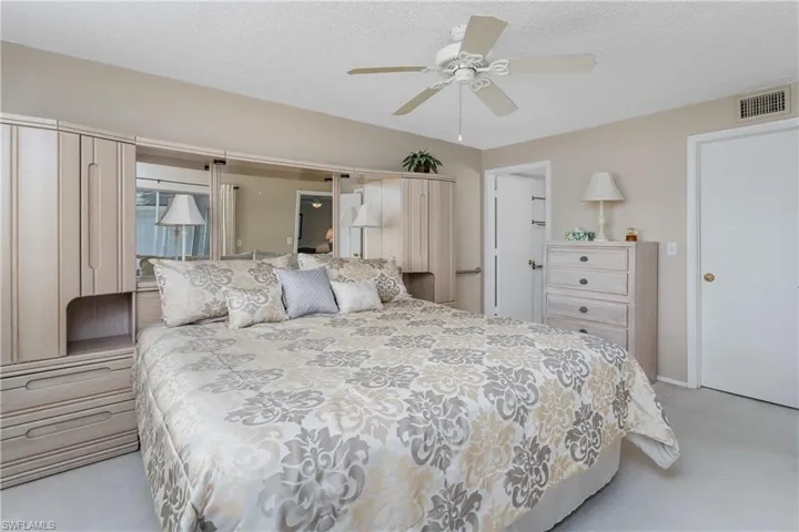 Bedroom featuring light colored carpet, ceiling fan, a textured ceiling, and visible vents