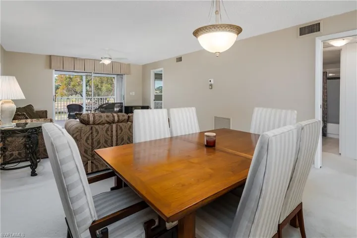 Dining area with a ceiling fan, visible vents, and light colored carpet
