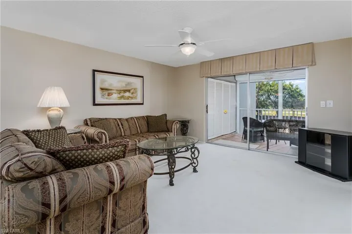 Living area featuring light carpet and ceiling fan