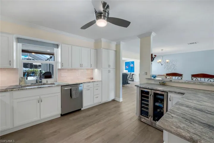 Kitchen featuring sink, stainless steel dishwasher, beverage cooler, and white cabinets
