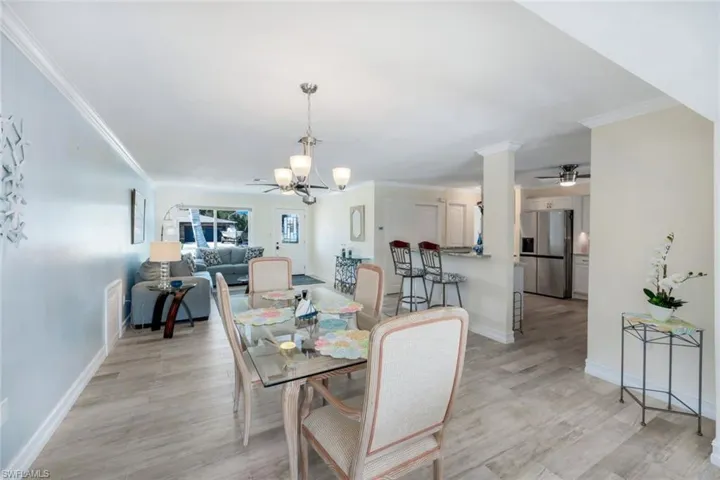 Dining room with crown molding, ceiling fan with notable chandelier, and light hardwood / wood-style floors