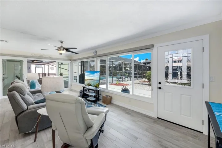 Living room with ceiling fan, ornamental molding, and light hardwood / wood-style floors