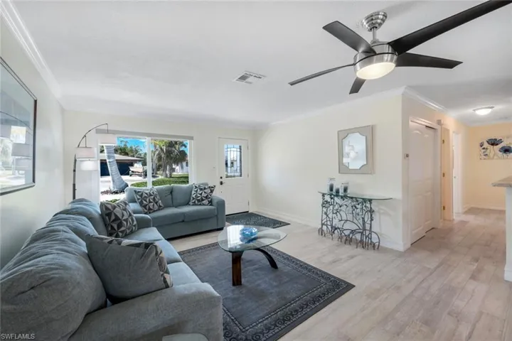 Living room featuring light hardwood / wood-style flooring, ornamental molding, and ceiling fan