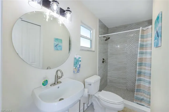 Bathroom featuring toilet, sink, and a shower with shower curtain