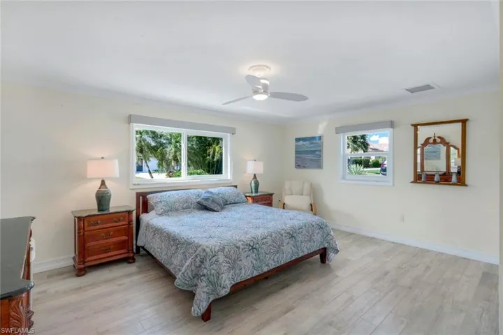 Bedroom with multiple windows, light hardwood / wood-style flooring, ornamental molding, and ceiling fan