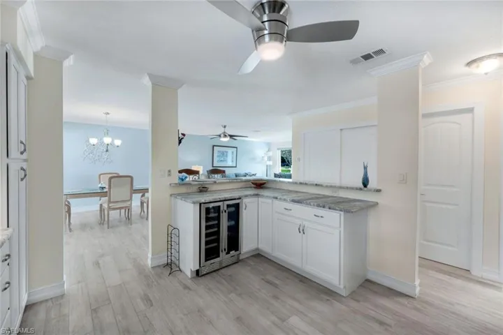Kitchen featuring wine cooler, white cabinetry, and crown molding