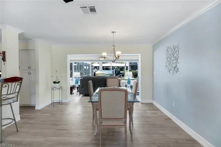 Dining area featuring crown molding, light hardwood / wood-style floors, and a notable chandelier