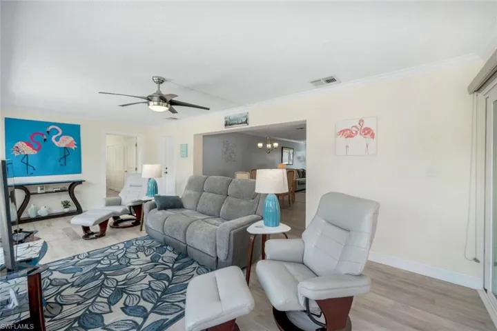 Living room featuring ceiling fan with notable chandelier, light hardwood / wood-style flooring, and ornamental molding