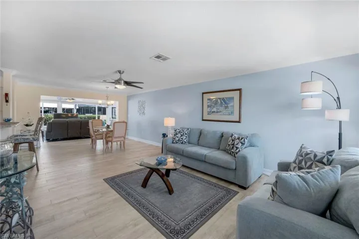 Living room featuring crown molding, ceiling fan with notable chandelier, and light wood-type flooring