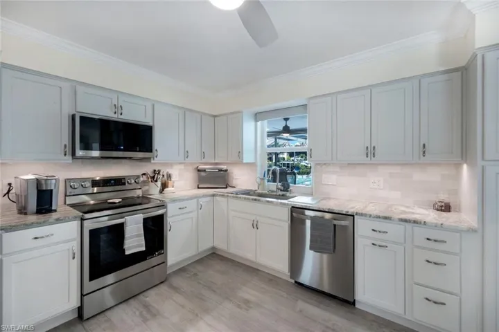 Kitchen with tasteful backsplash, sink, ceiling fan, stainless steel appliances, and light hardwood / wood-style flooring