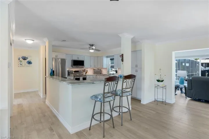 Kitchen with light wood-type flooring, ornate columns, and appliances with stainless steel finishes
