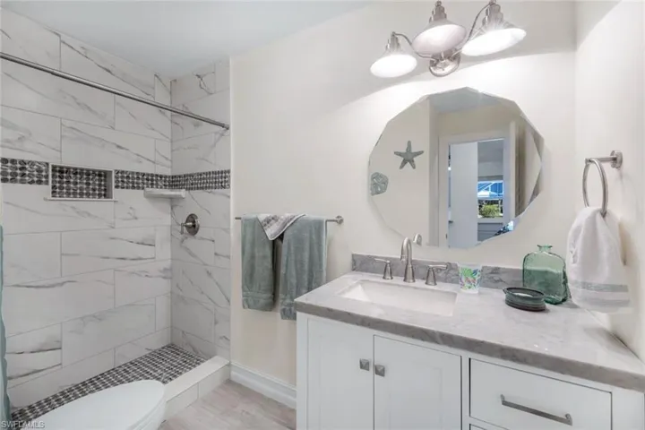 Bathroom with vanity, a tile shower, and toilet