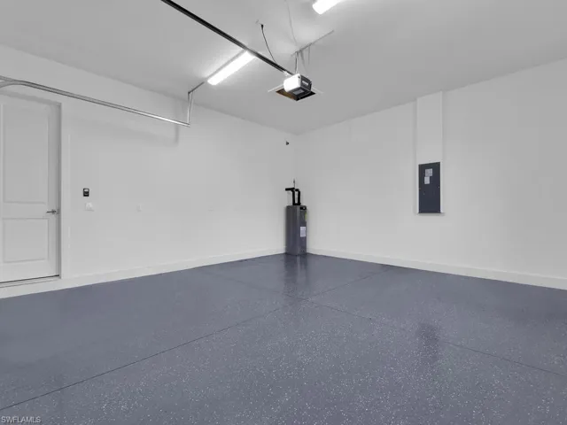Garage featuring electric panel, water heater, and a garage door opener.