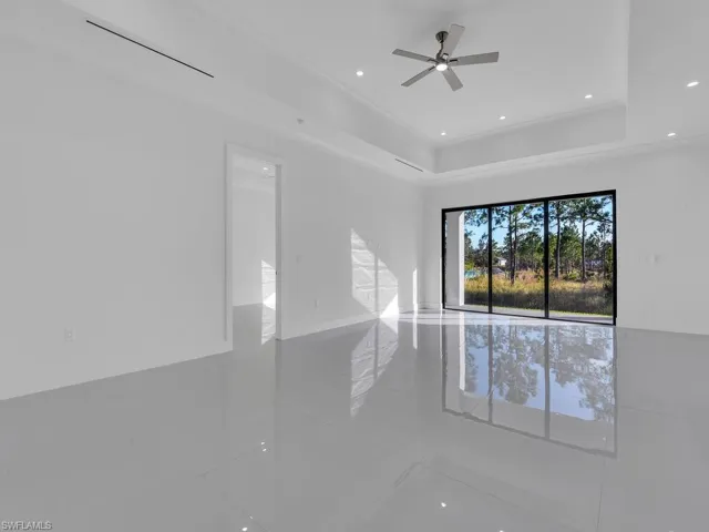 Tiled empty room featuring a raised ceiling and ceiling fan
