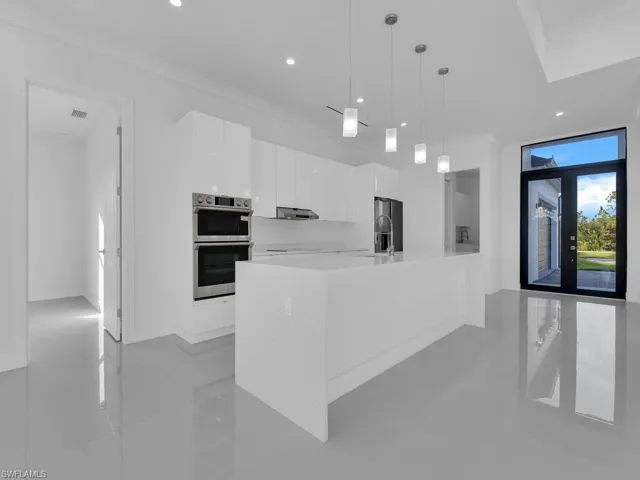 Kitchen featuring french doors, crown molding, hanging light fixtures, double oven, and white cabinetry