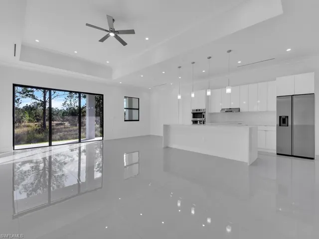 Unfurnished living room with ceiling fan, a raised ceiling, and light tile patterned floors