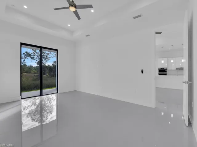 Unfurnished room featuring a raised ceiling, ceiling fan, and tile patterned flooring