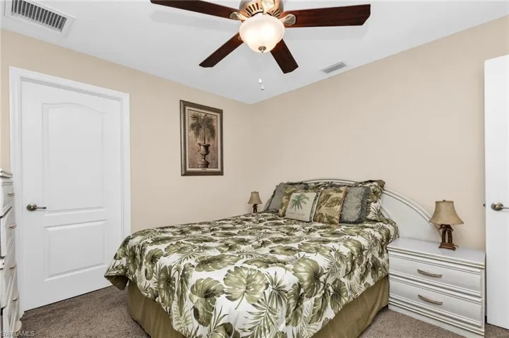Neutral wall color with a ceiling fan light fixture, carpeted flooring, and a white interior door