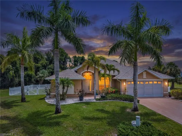 Single-story residence featuring a stucco exterior, an arched entryway, a two-car garage, and mature palm trees